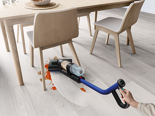 The Wash G1 being used to clean up a wet mess underneath the table and chairs of a dining room.