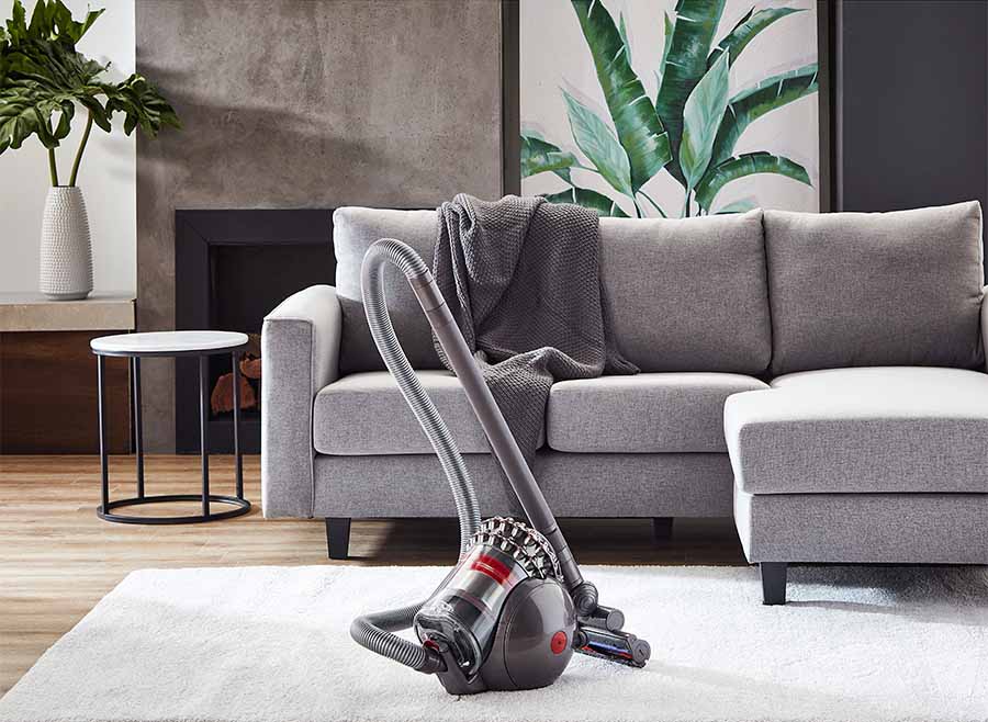 A Dyson Cinetic Big Ball Vacuum pictured next to a couch.