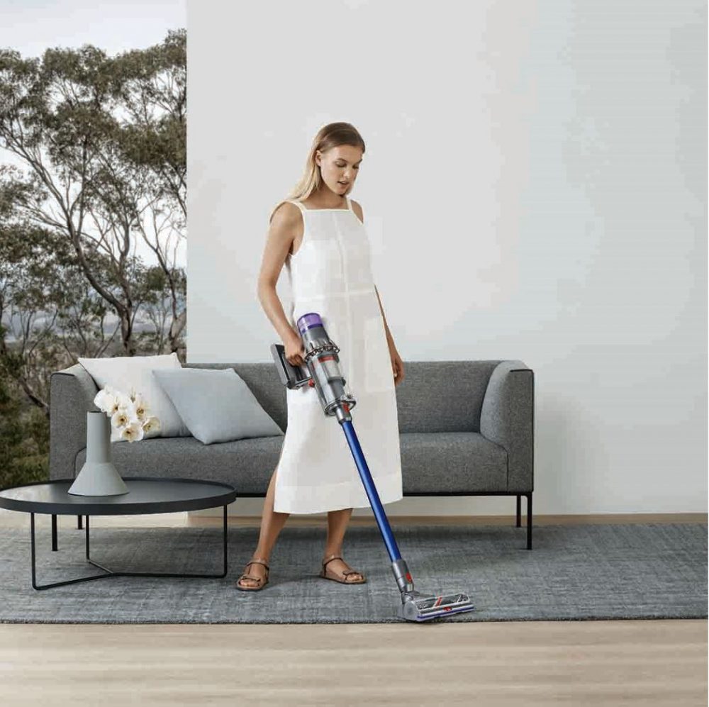 A woman using the Dyson V11 Absolute Extra to clean the lounge room carpet.