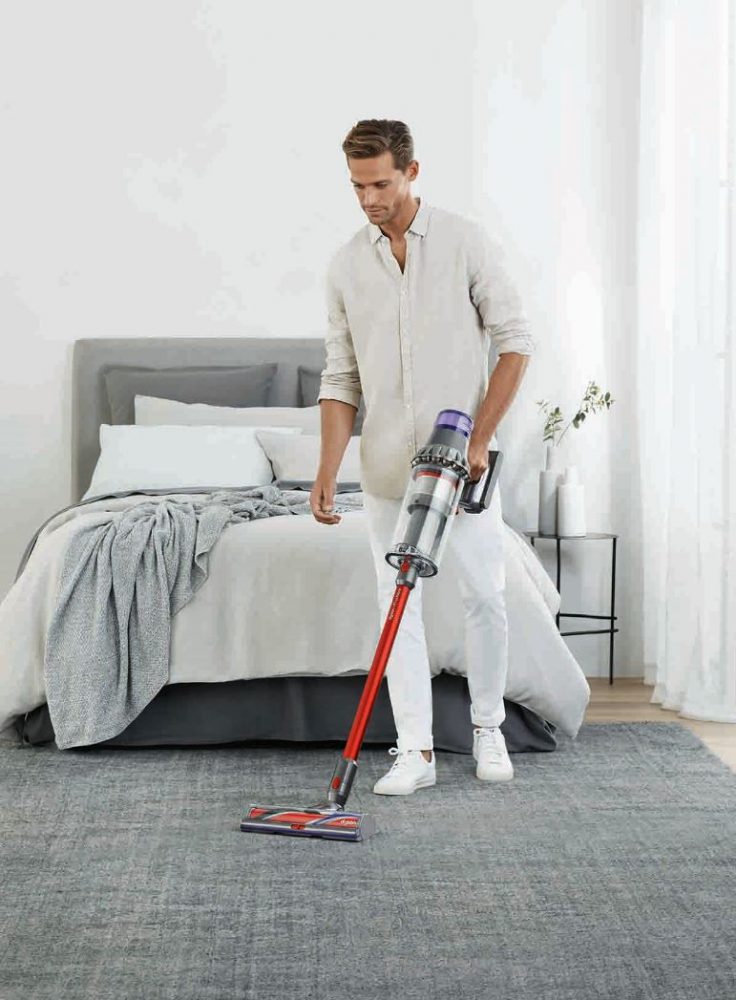 A man cleaning the bedroom floor with the Dyson V11 Outsize Cordless Vacuum Cleaner.