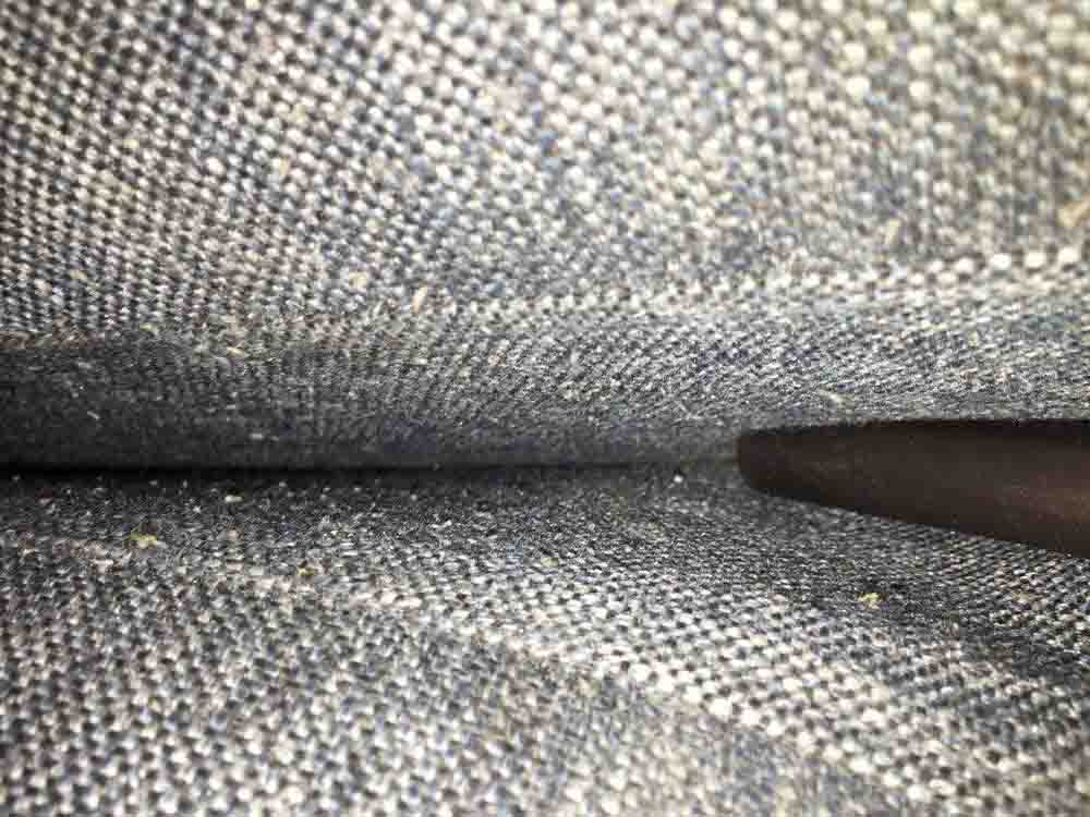 The crevice tool of the Dyson V11 Absolute Extra Cordless Vacuum pictured in between the seat cushions of a sofa it has cleaned.