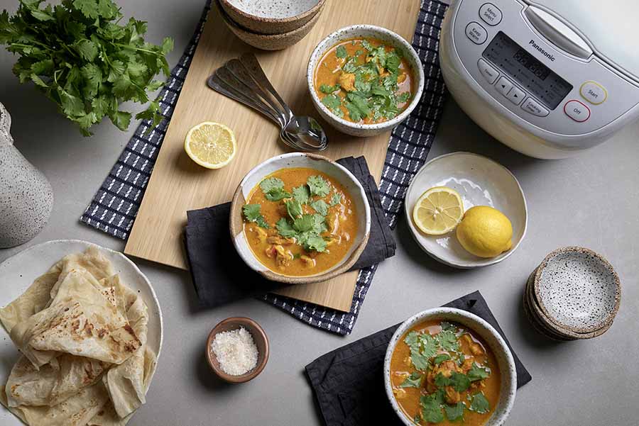 Three bowls of Kenyan Chicken Curry next to a Panasonic Rice Cooker.