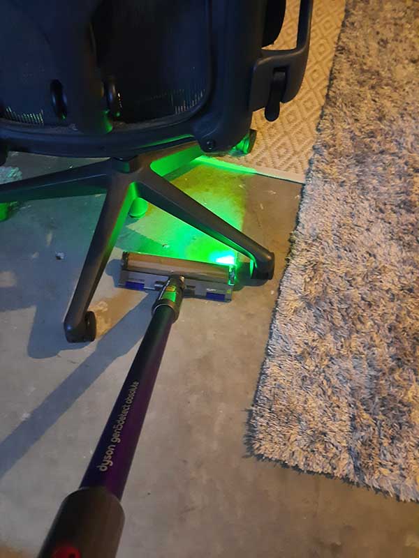 The Dyson Gen5detect's laser revealing hidden dust on a floor.