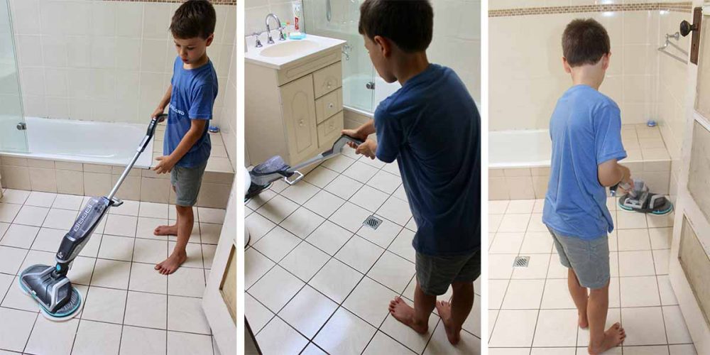 Our reviewer's son using the Bissell SpinWave Cordless Mop to clean the bathroom floors.