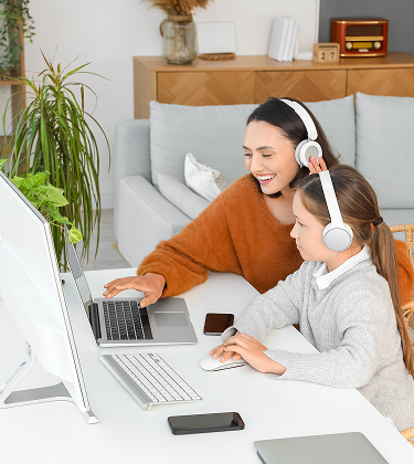 Smiling woman and child both wearing headphones while looking at laptop screen, representing Wi-Fi 7 connectivity